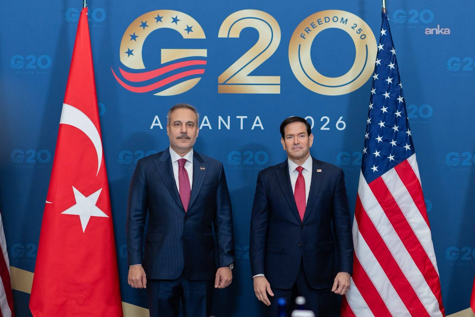 Hakan Fidan ve Marco Rubio, G20 Atlanta 2026 fonu önünde Türk ve ABD bayrakları arasında poz veriyor.