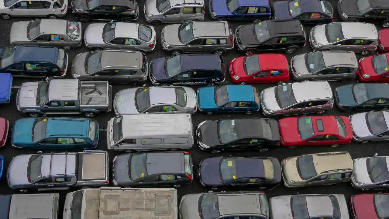 Çok sayıda otomobilin yer aldığı otopark görünümü.