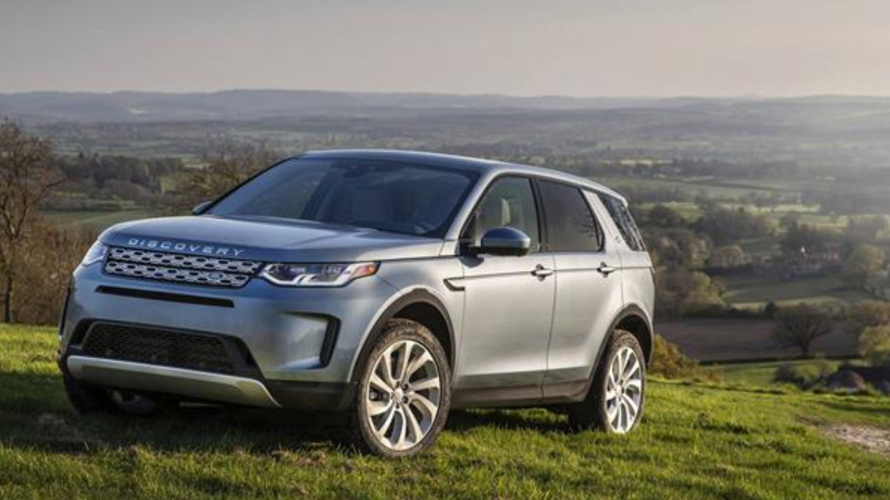 Kırsal manzara önünde duran gri Land Rover Discovery Sport.