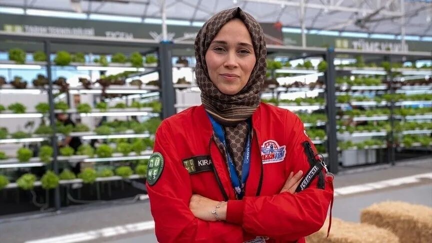 A female agricultural entrepreneur posing in a red work uniform in a modern production area.