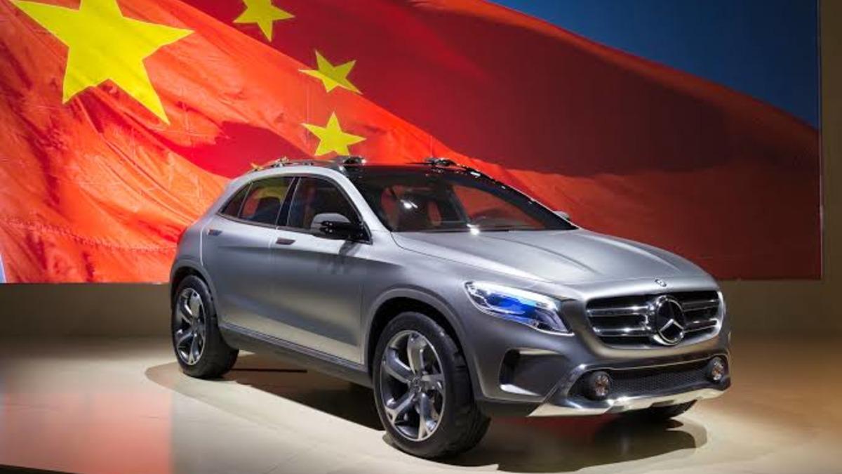 A gray Mercedes-Benz SUV model displayed in front of a Chinese flag background.