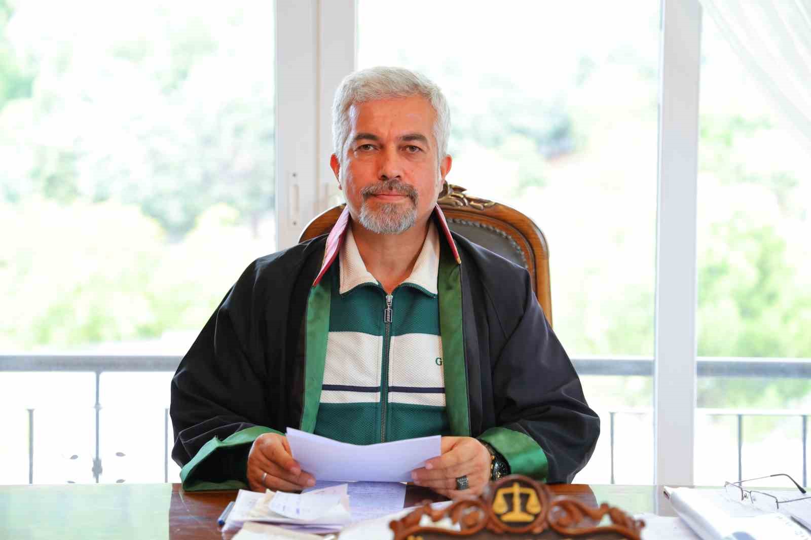 Foto dell'avvocato Özcan Kara alla scrivania con dei documenti.