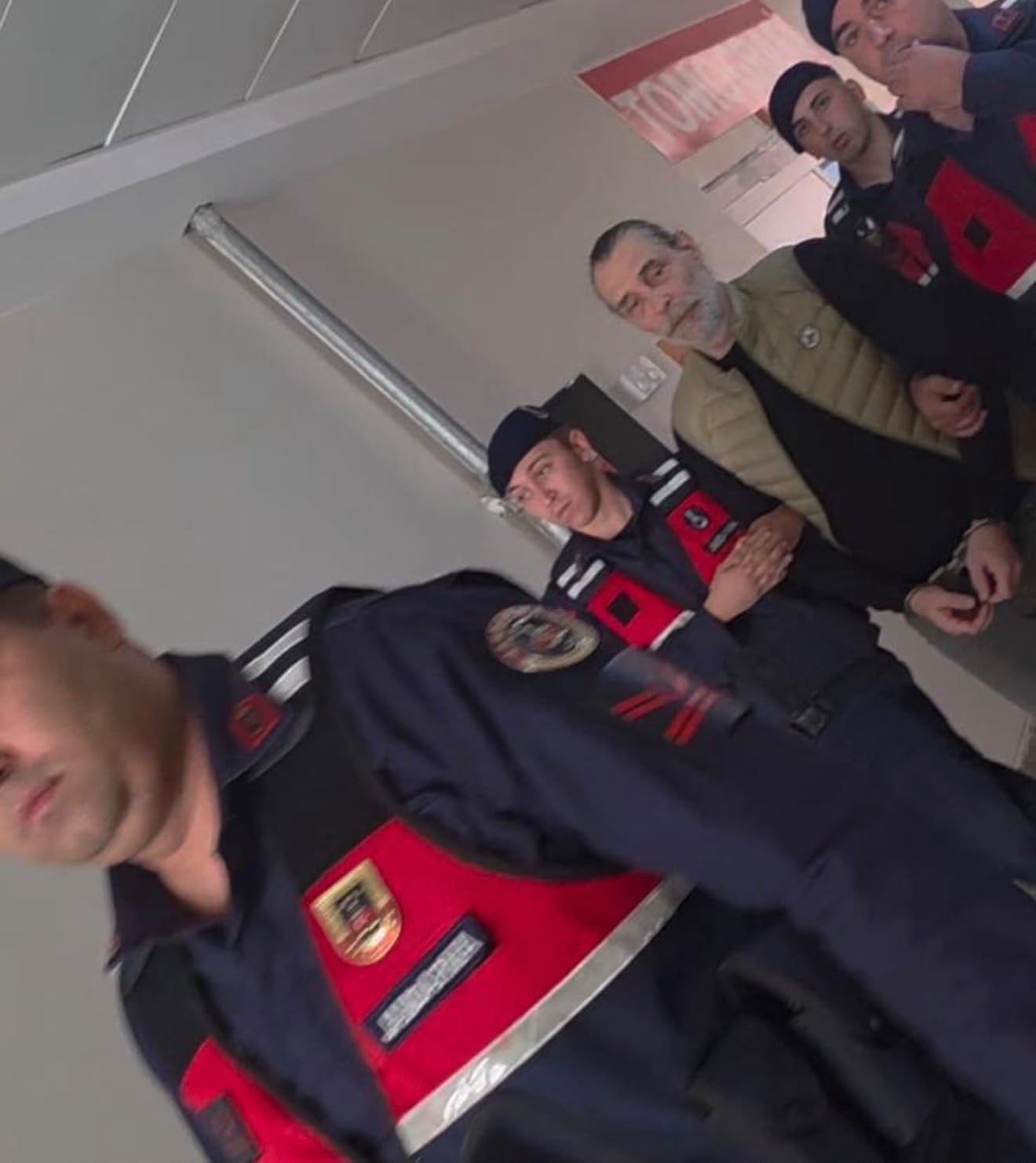 Erdal Beşikçioğlu is seen in the hospital corridor accompanied by security guards.