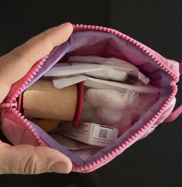 İçinde sargı bezi, gazlı bez ve benzeri ilk yardım malzemeleri bulunan pembe bir çanta.