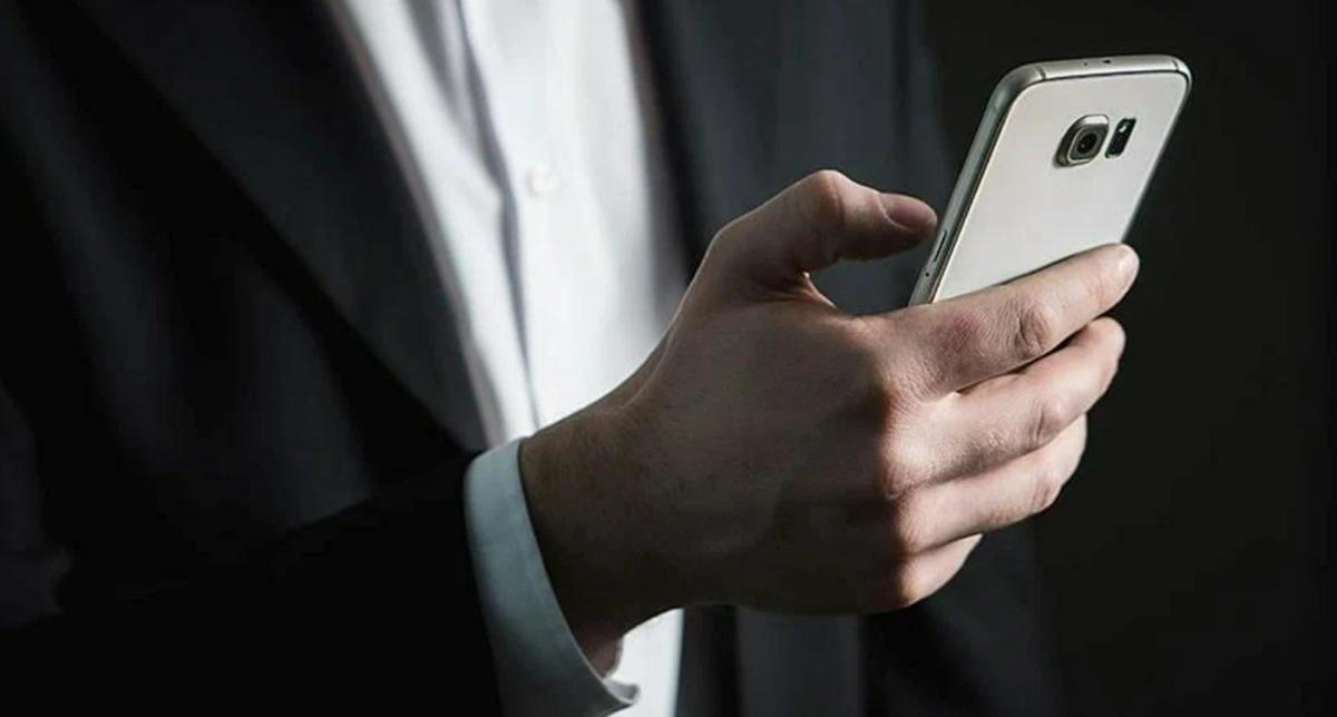 Elinde telefon tutan bir kişi, bankacılık işlemlerini takip ediyor.