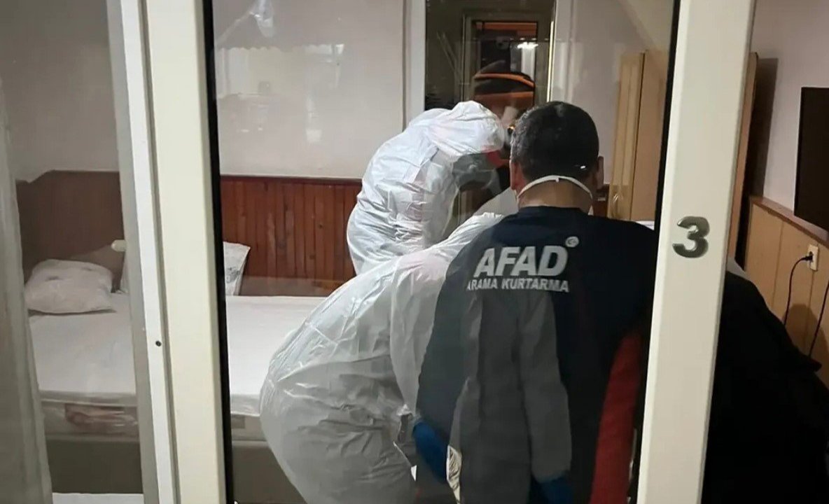 Officials in AFAD vests and protective gear conducting an investigation in the guesthouse room.