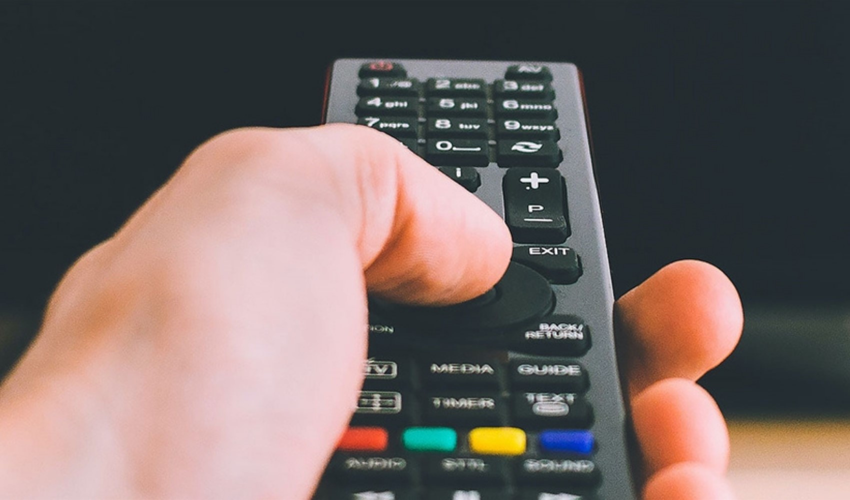 Televizyon kumandasına basan bir elin yakın plan görüntüsü