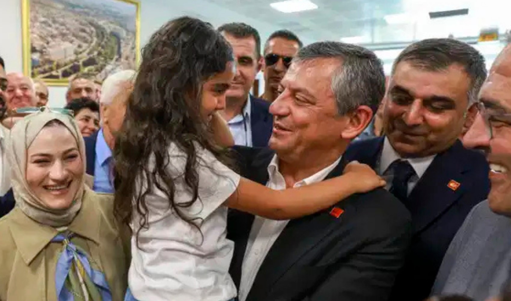 Özgür Özel, kalabalık bir karşılamada bir çocukla birlikte görülüyor.