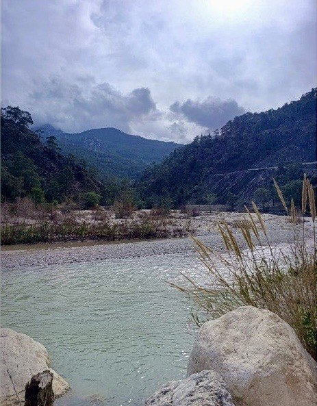 Dağlık ve ormanlık bir bölgede akan dere yatağı ve çevresindeki doğal görünüm.