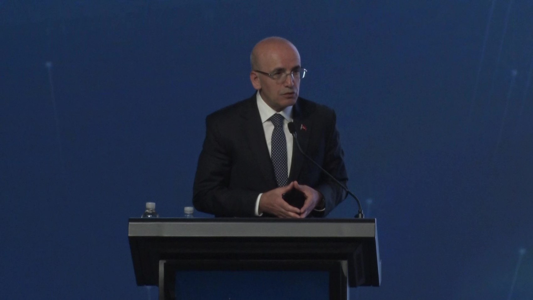 A figure from the economic management speaking at a podium.