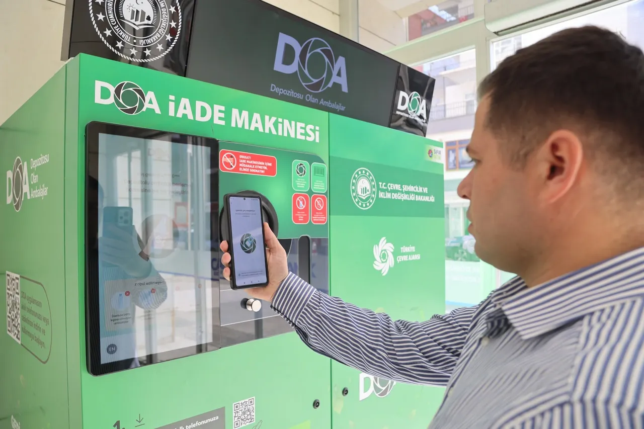 Bir kullanıcının DOA iade makinesi önünde cep telefonunu tuttuğu görülüyor.