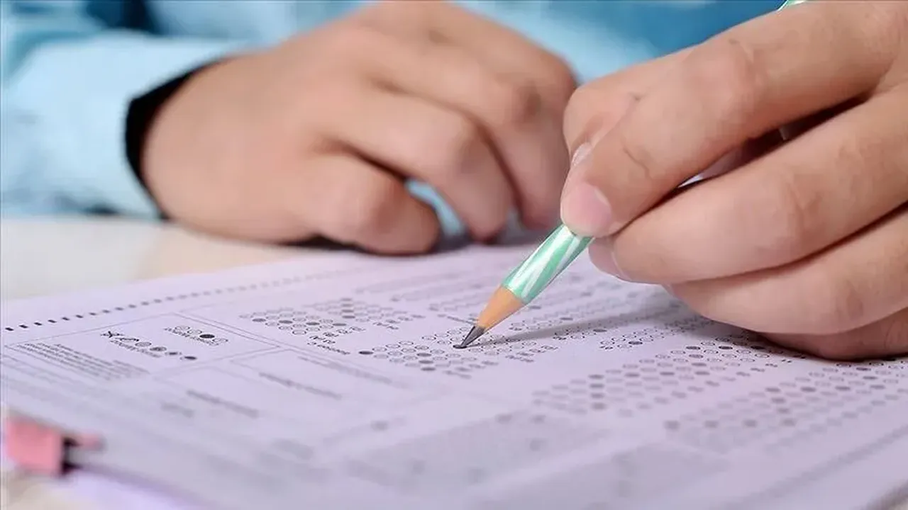 Optik form üzerinde kalemle işaretleme yapan aday eli.
