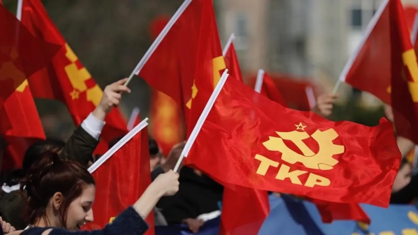 TKP bayrakları taşıyan katılımcıların yer aldığı kalabalık bir etkinlik görüntüsü.