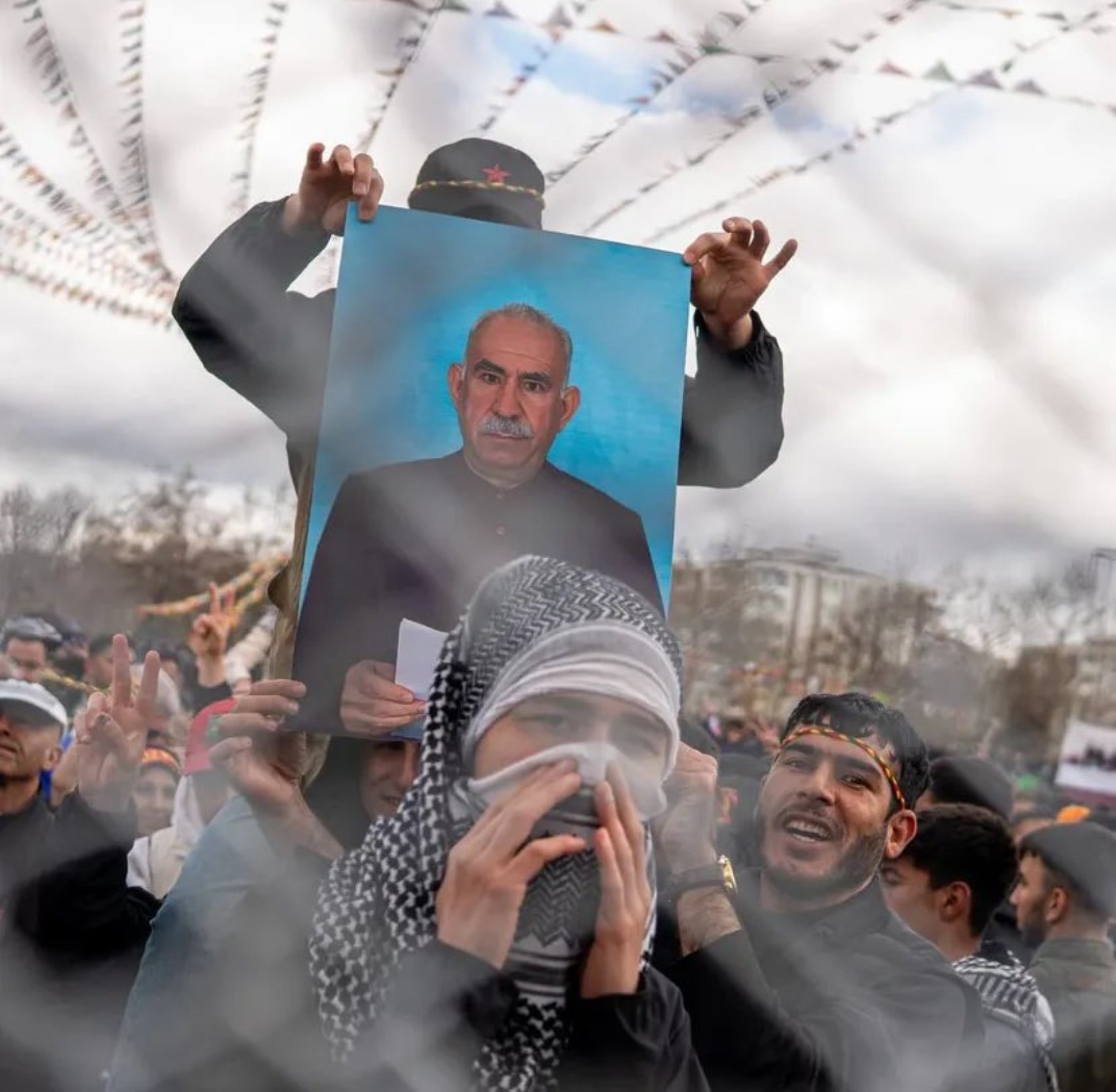Kalabalık bir etkinlikte Abdullah Öcalan posterinin taşındığı an görülüyor.