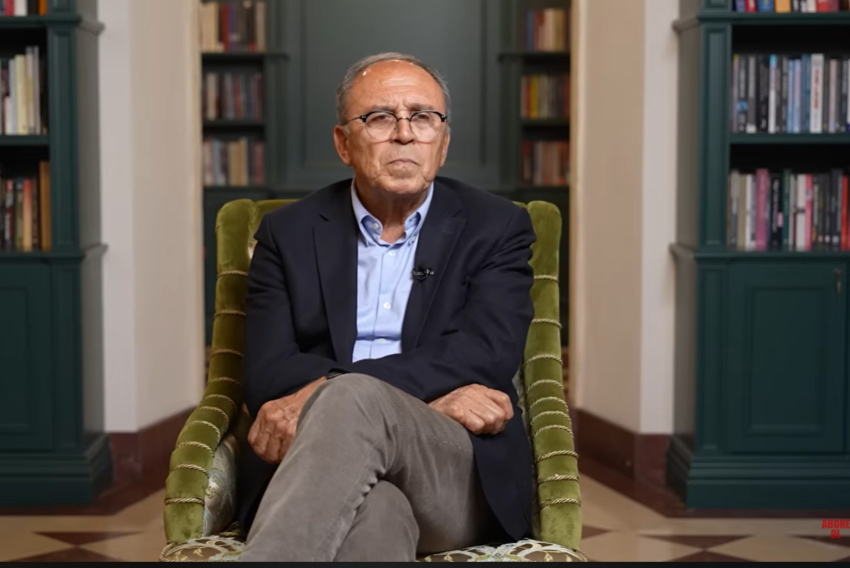 Kitaplıkların bulunduğu bir odada koltukta oturan Ahmet Yavuz.