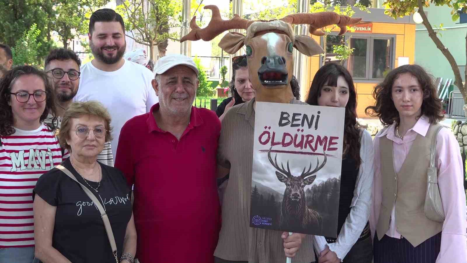 Geyik kostümlü katılımcı, protestocularla birlikte “Beni öldürme” yazılı dövizi tutuyor.