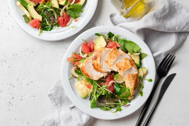 Beyaz tabakta ızgara tavuk ve avokado salatası.