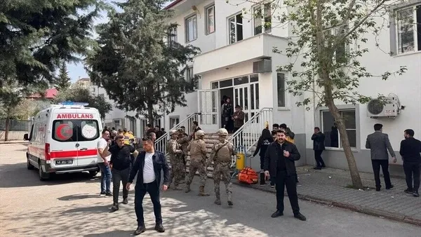 Okul binası çevresinde güvenlik görevlileri, ambulans ve vatandaşlar görülüyor.
