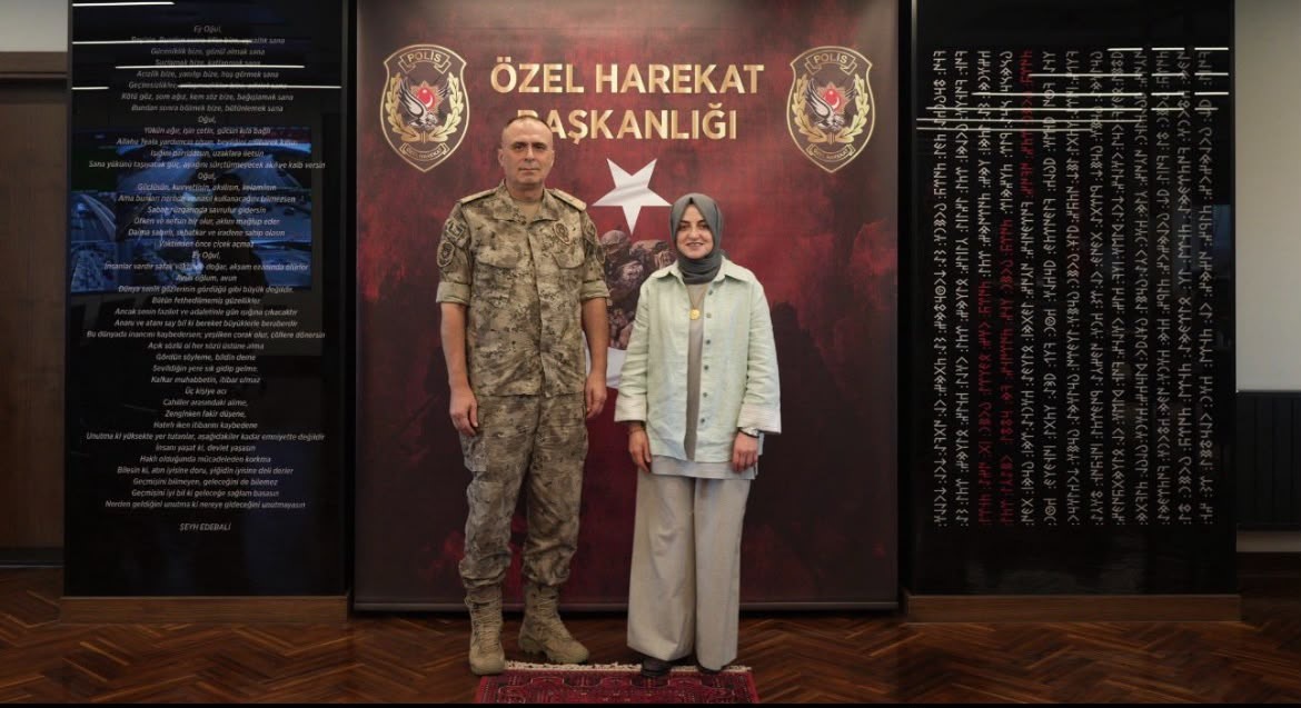 Gülşen Orhan ve Ünsal Hayal, Özel Harekat Başkanlığı yazısının bulunduğu panonun önünde yan yana duruyor.