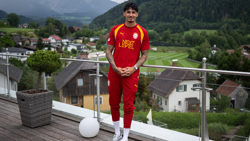 Galatasaray forması giyen Uğurcan Çakır, Avusturya kampında dağ manzaralı bir alanda poz veriyor.