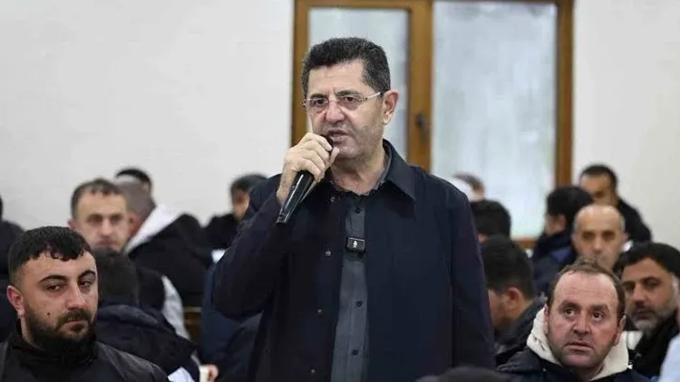 Orhan Çerkez bir toplantıda mikrofonla konuşurken görülüyor.