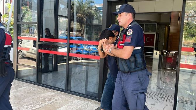 Jandarma ekiplerinin şüpheliyi adliye binası önünde götürdüğü anı gösteren fotoğraf.