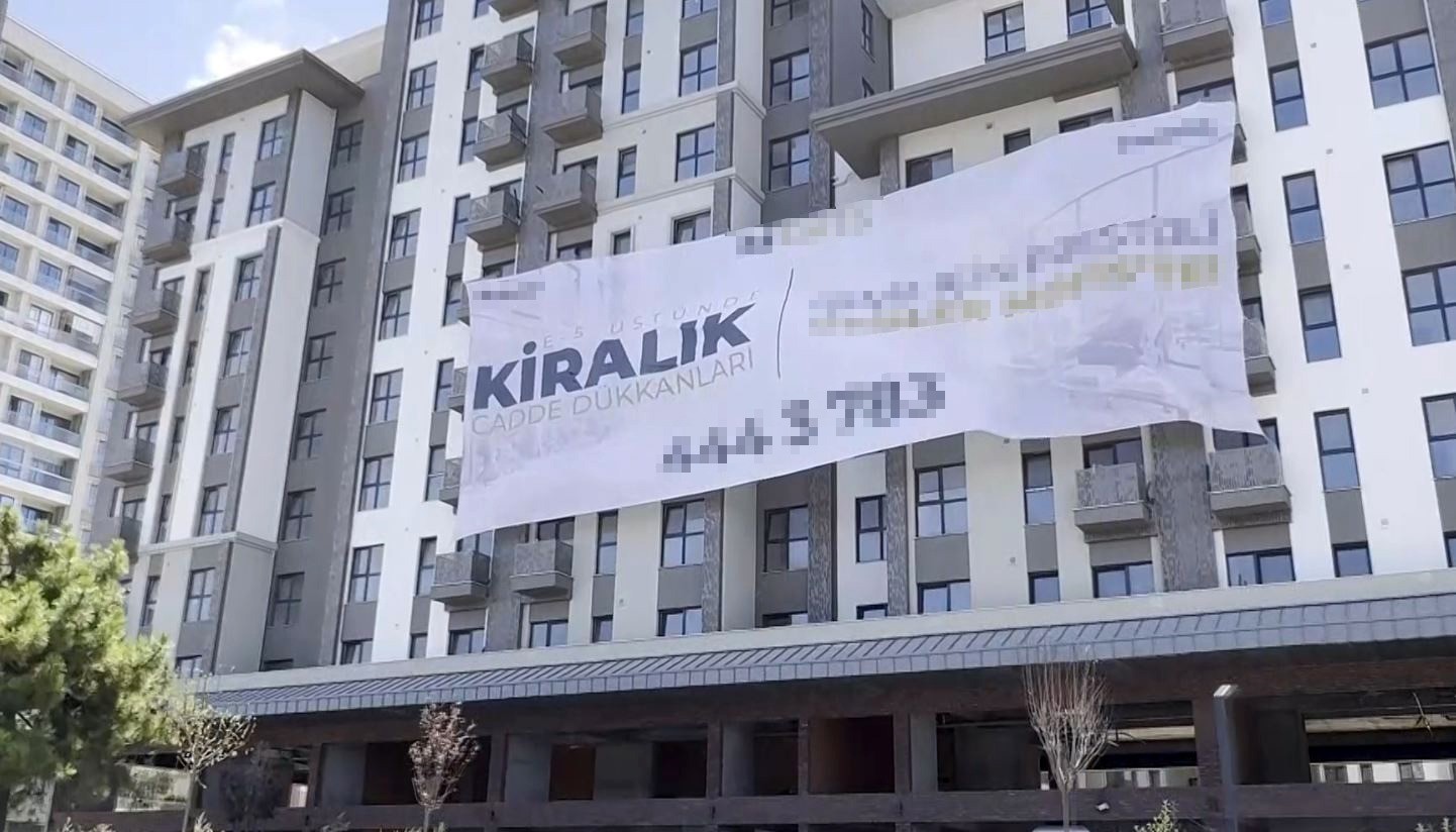 Bir binanın cephesinde kiralık cadde dükkanları ilanı yer alıyor.