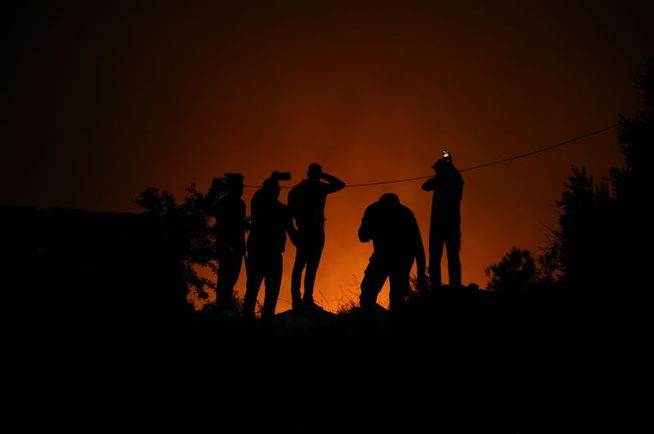 Yangın bölgesinde gece alevleri izleyen ekiplerin silüetleri.