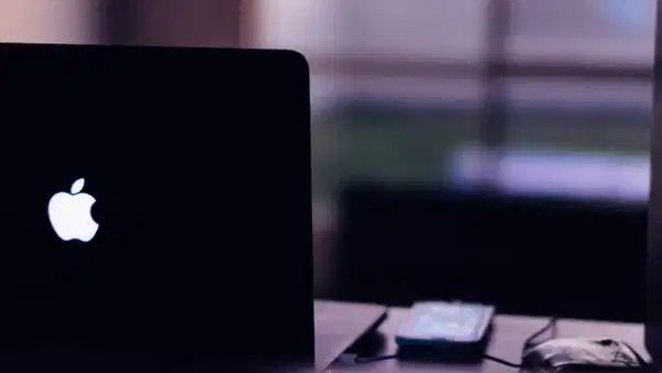 Karanlık ortamda parlayan Apple logolu dizüstü bilgisayar