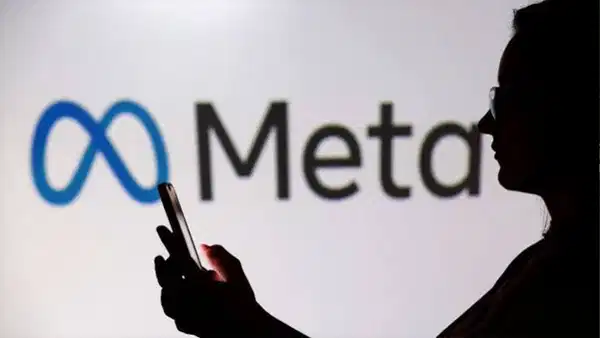 Meta logosu önünde telefon kullanan bir kişinin silüeti