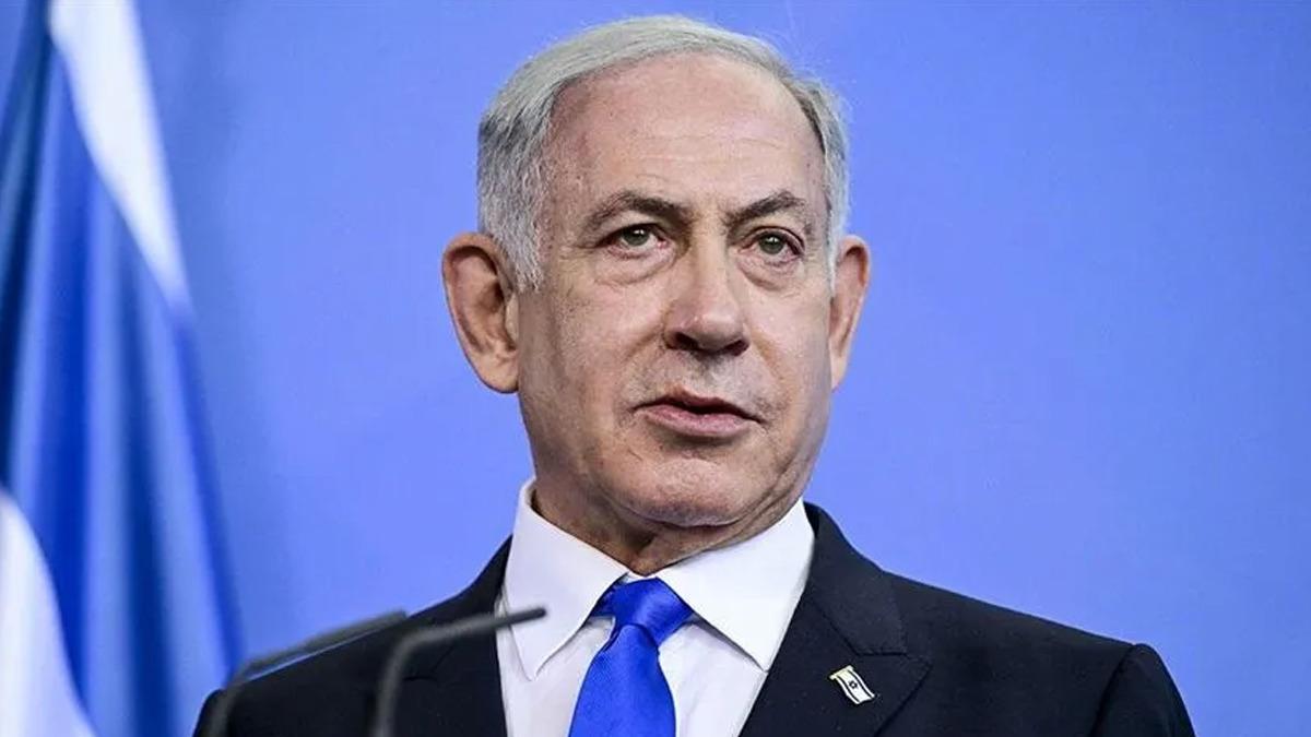 Binyamin Netanyahu kürsü önünde mavi arka planla görülüyor.