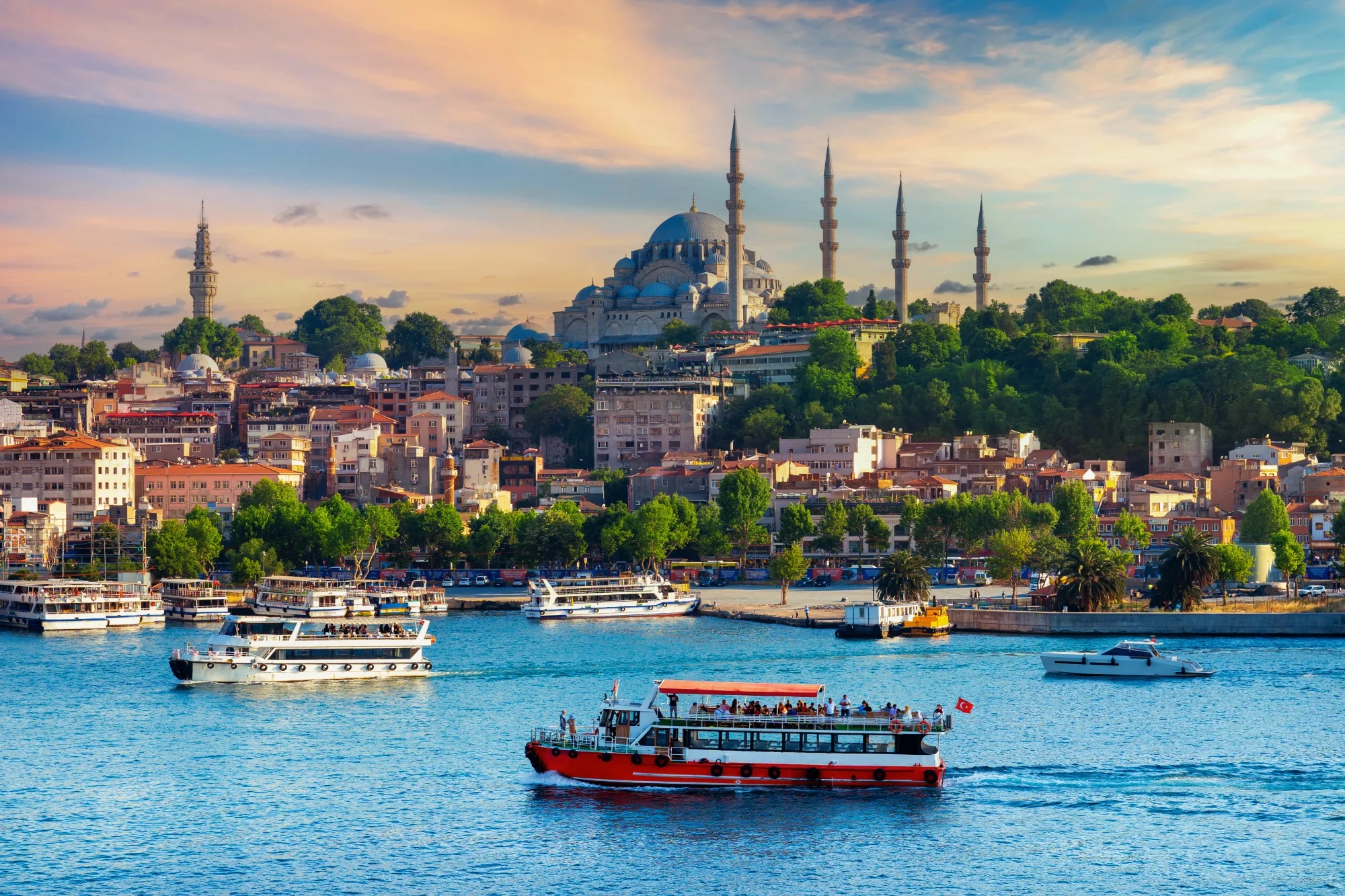 İstanbul’da deniz, tekneler ve tarihi cami silüetinin bulunduğu manzara.