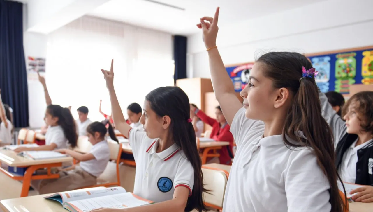 Sınıfta ders işleyen ve parmak kaldıran öğrenciler.