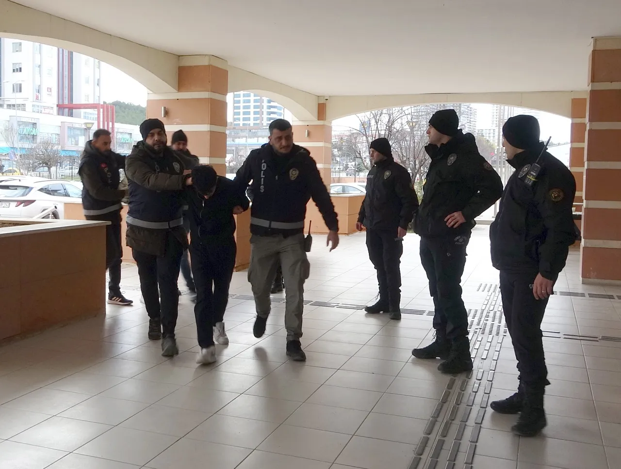 Polis ekiplerinin adliye koridorunda bir şüpheliyi götürdüğü görüntü.