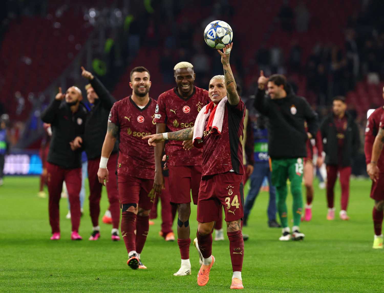 Lucas Torreira topu elinde tutarken Galatasaraylı futbolcular sahada görülüyor.