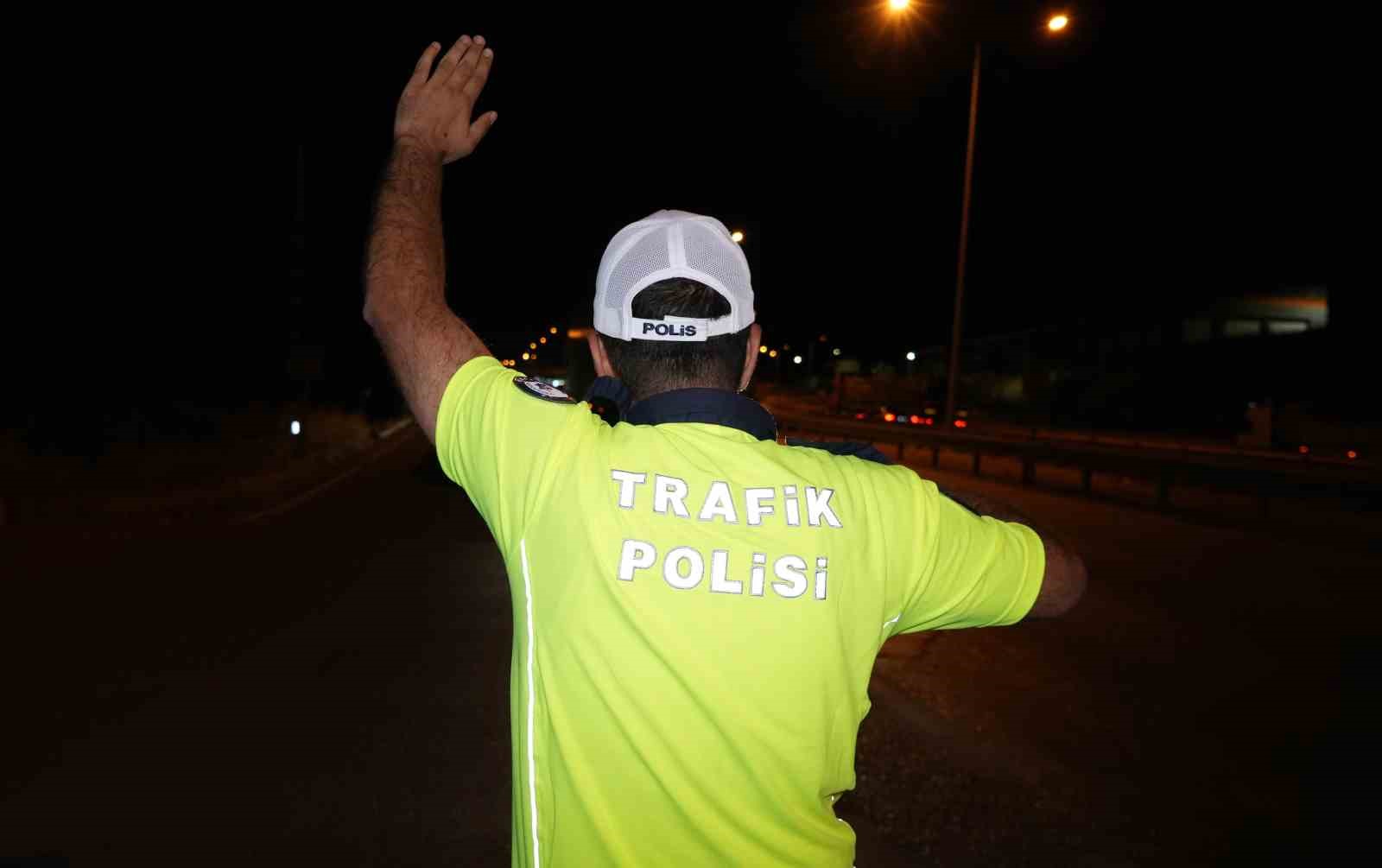 Gece yol üzerinde araçlara yönlendirme yapan trafik polisi.