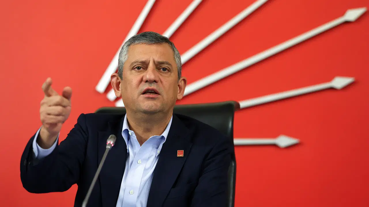 CHP Genel Başkanı Özgür Özel, kırmızı CHP amblemi önünde konuşma yaparken görülüyor.