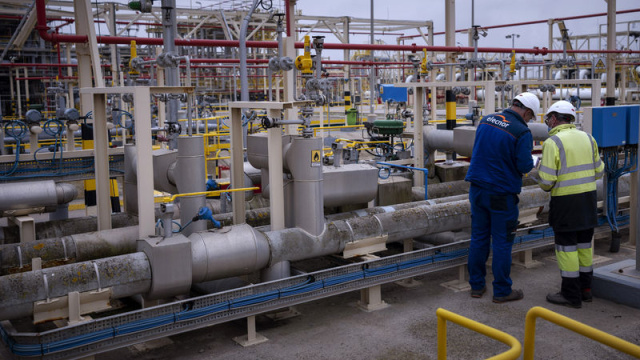 Doğalgaz tesisinde boru hatları ve teknik ekipmanlar arasında çalışan görevliler.