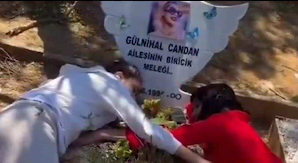 İki kişinin Nihal Candan’ın mezarı üzerinde sarıldığı bir görüntü.
