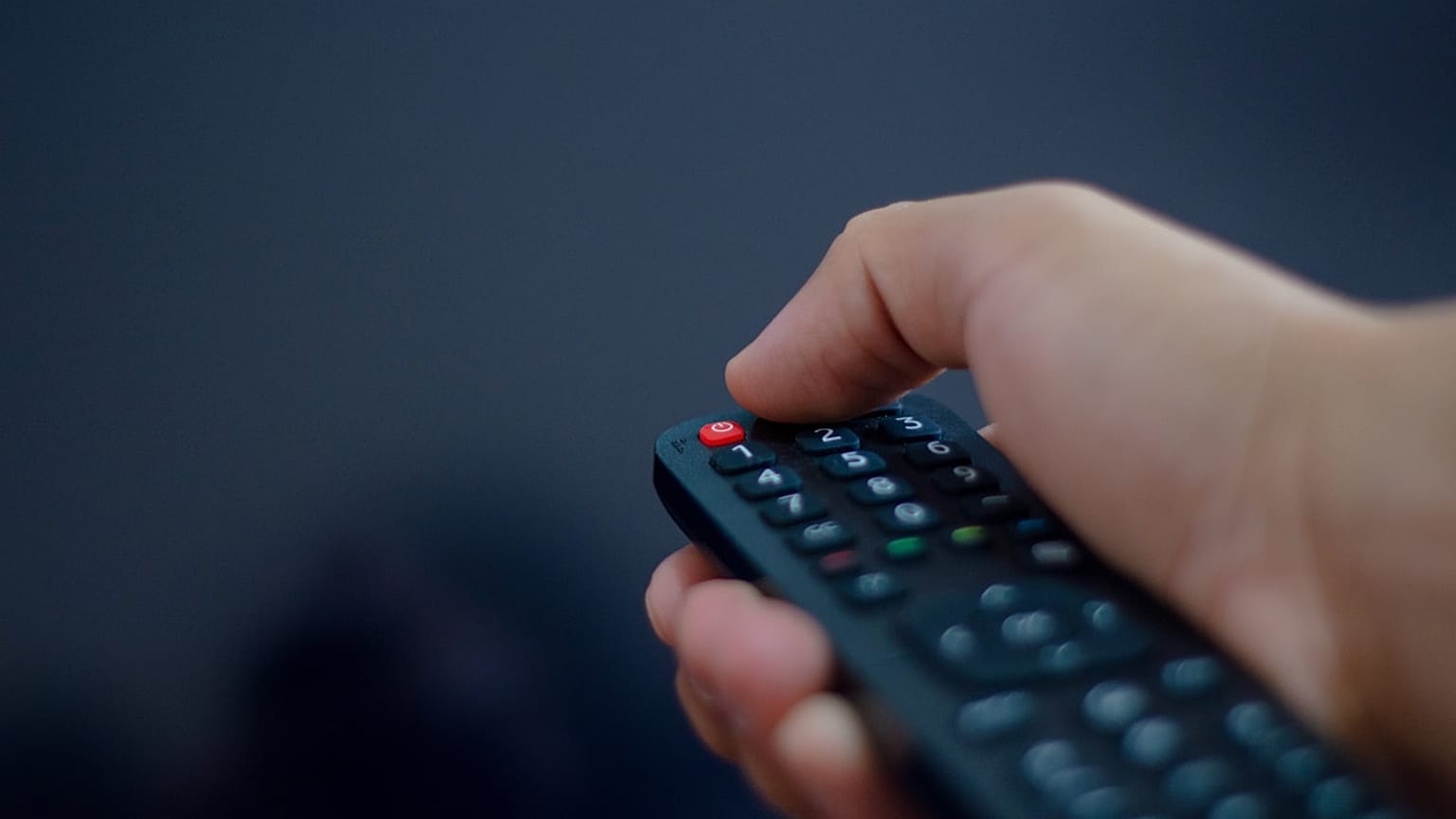 Televizyon kumandası kullanan bir elin yakın plan görüntüsü