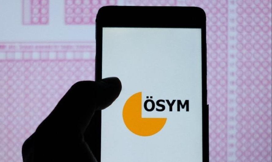 Telefon ekranında ÖSYM logosu ve arka planda sınav kağıdı.