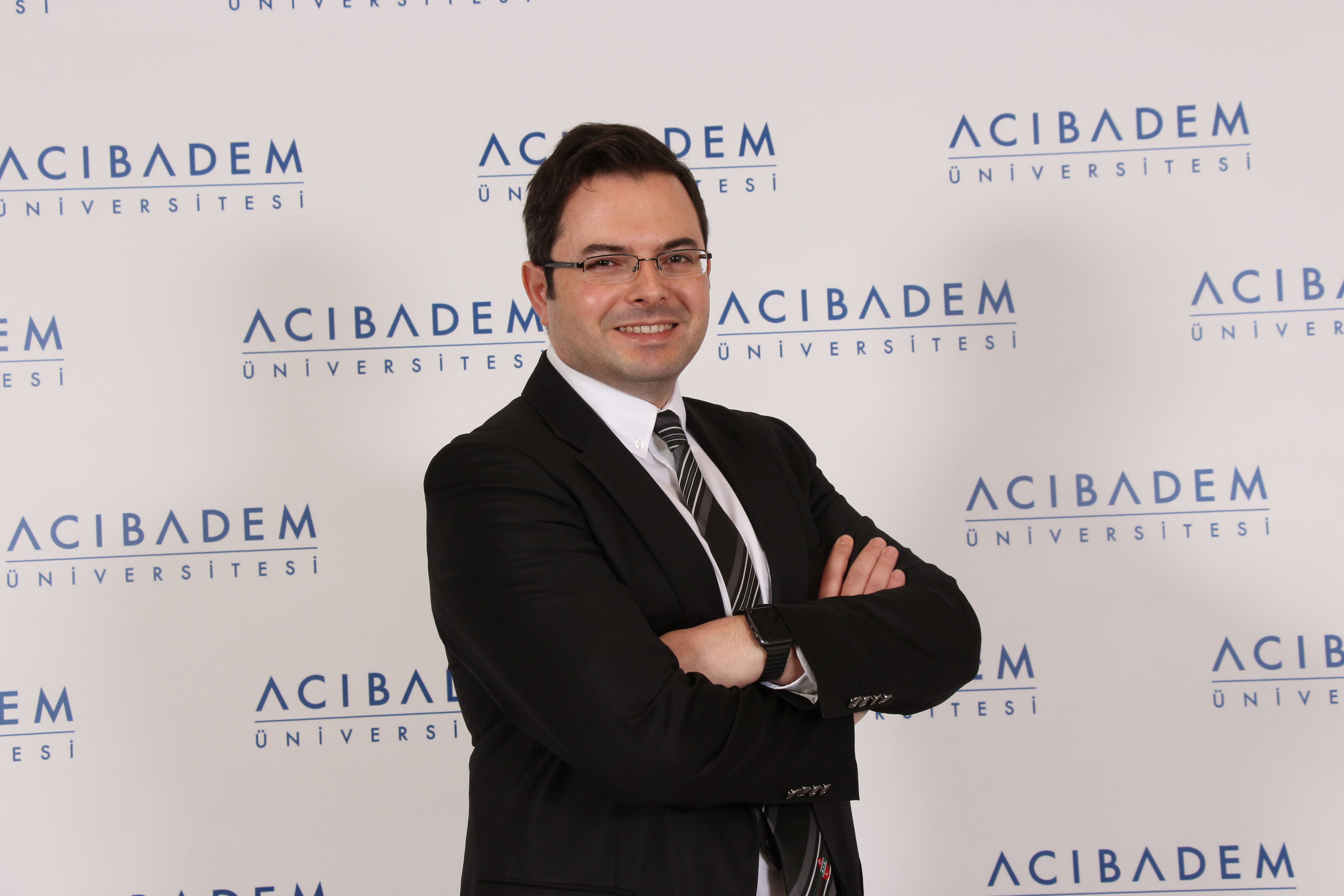 Acıbadem Üniversitesi logosunun bulunduğu arka plan önünde bir akademisyen portresi.