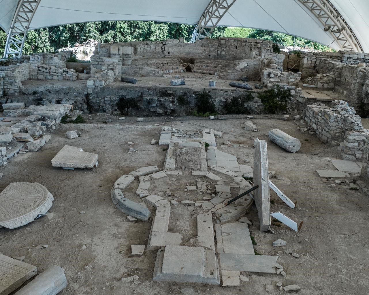 Koruma örtüsü altındaki Kadıkalesi-Anaia Höyüğü kazı alanında taş duvarlar, sütun parçaları ve mimari kalıntılar yer alıyor.
