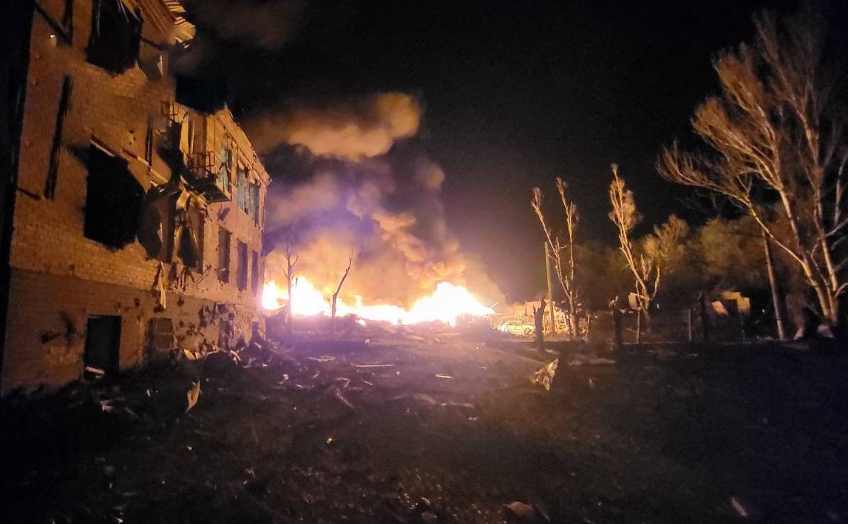 Gece saatlerinde saldırı sonrası alevlerin yükseldiği hasarlı yerleşim alanı.