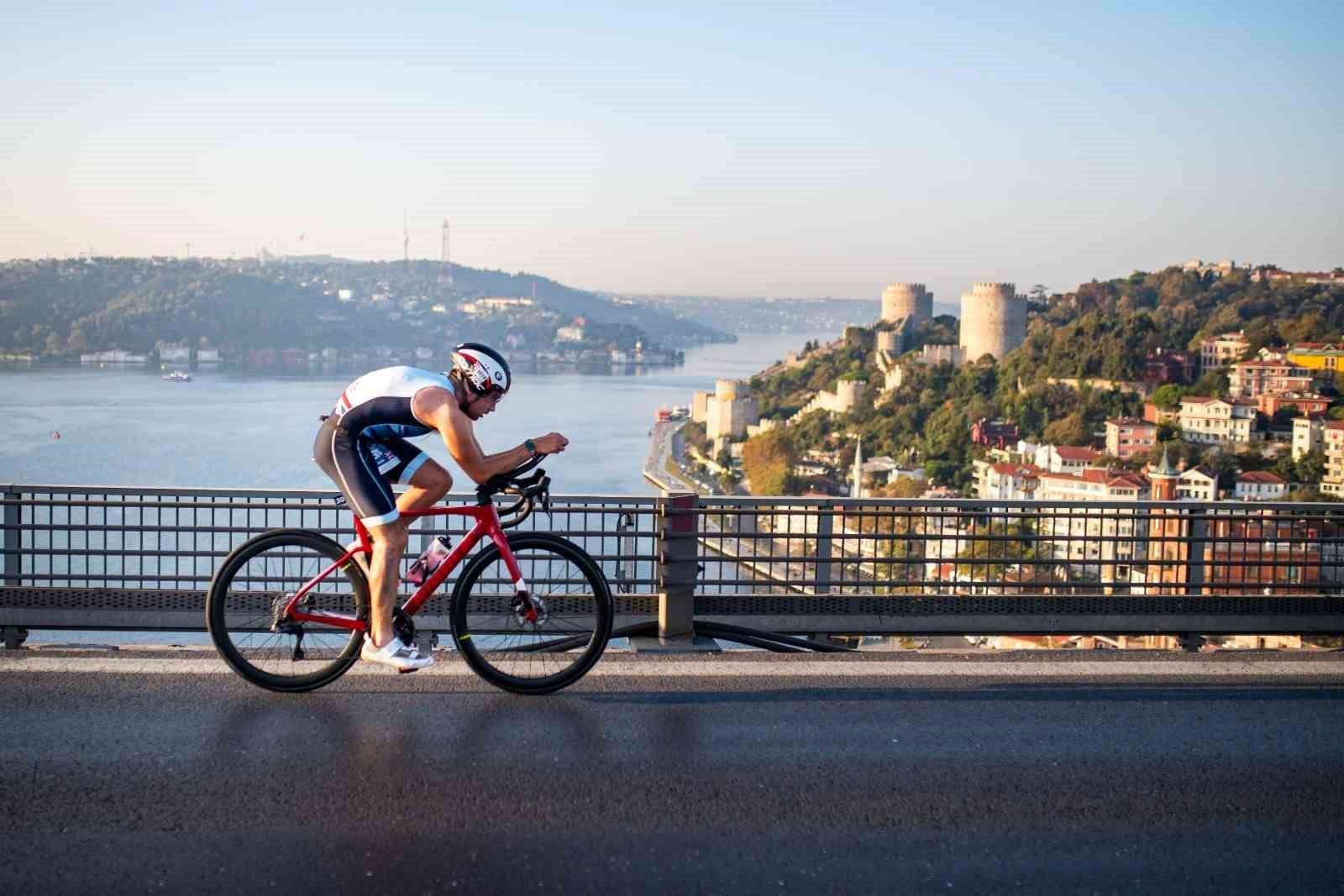 İstanbul Boğazı manzarasında köprü üzerinde bisiklet süren triatlet.