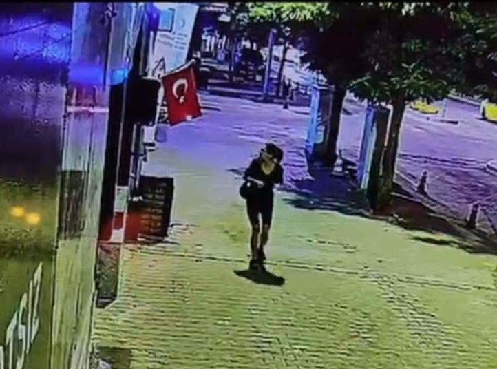 Güvenlik kamerası görüntüsünde mağaza önünde asılı Türk bayrağı ve şüpheli görülüyor.