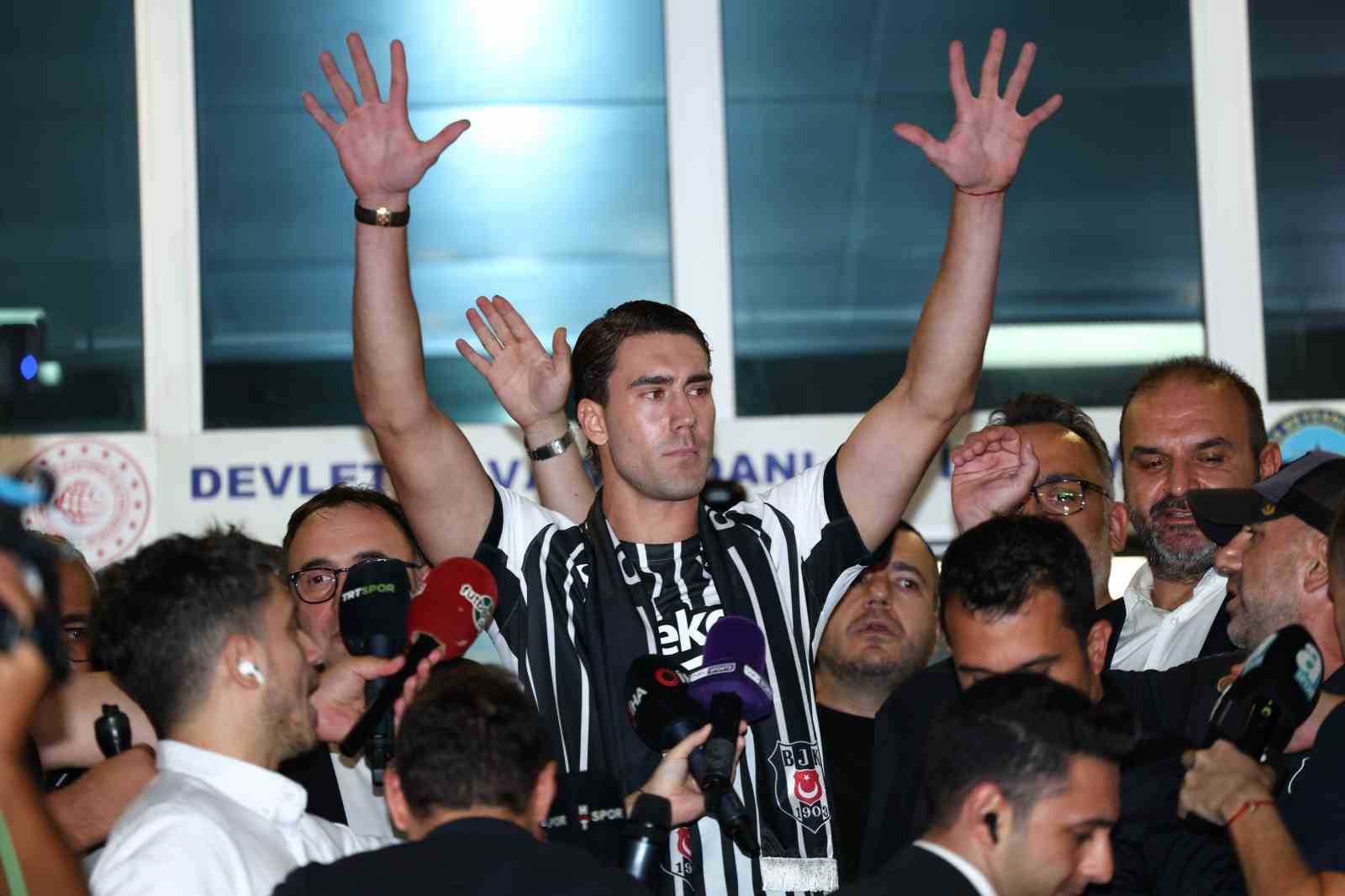 Dusan Vlahovic, Beşiktaş atkısıyla havalimanı çıkışında iki elini kaldırarak taraftarları selamlıyor.