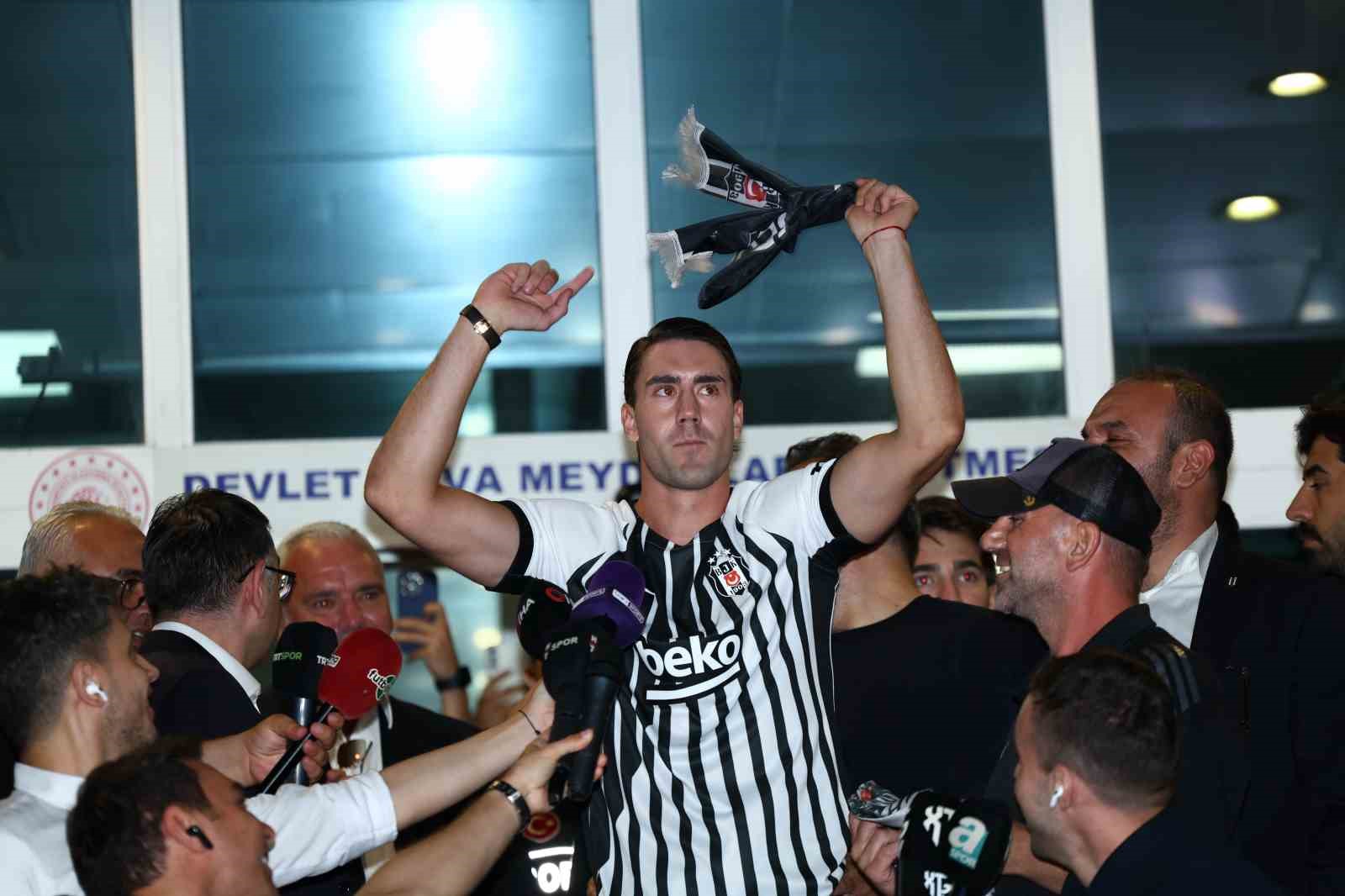 Dusan Vlahovic, Beşiktaş forması ve atkısıyla basın mensuplarının yanında görülüyor.