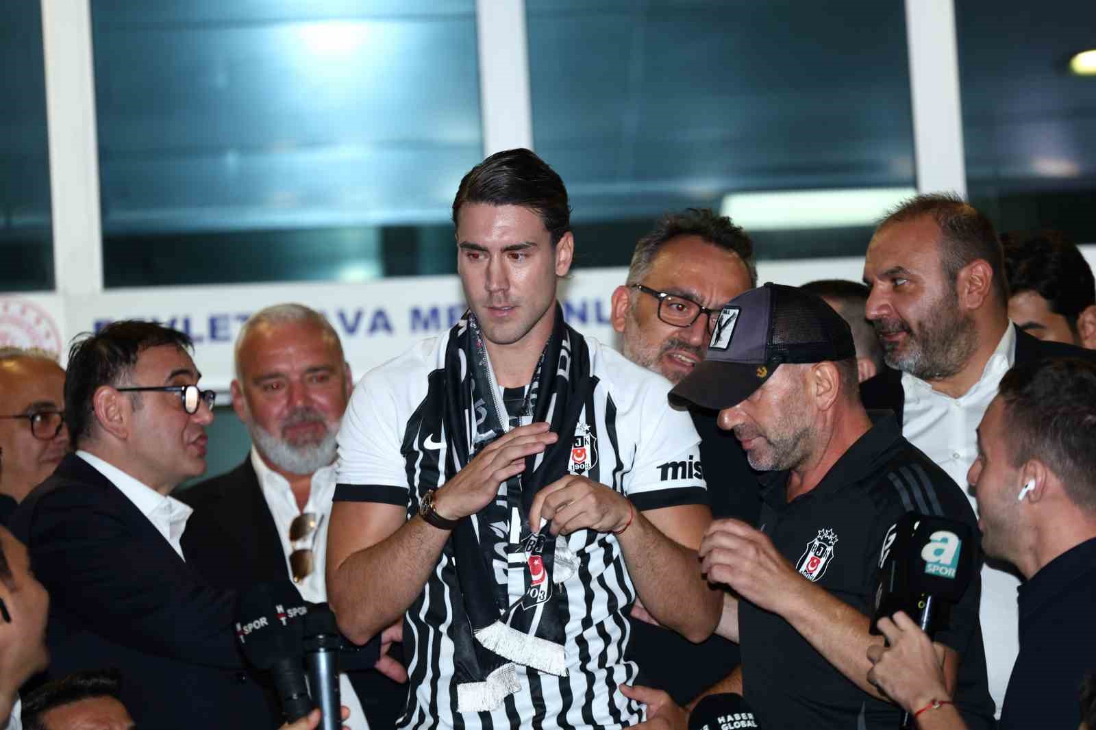 Dusan Vlahovic, Beşiktaş atkısını tutarken kulüp görevlileri ve basın mensupları yanında yer alıyor.