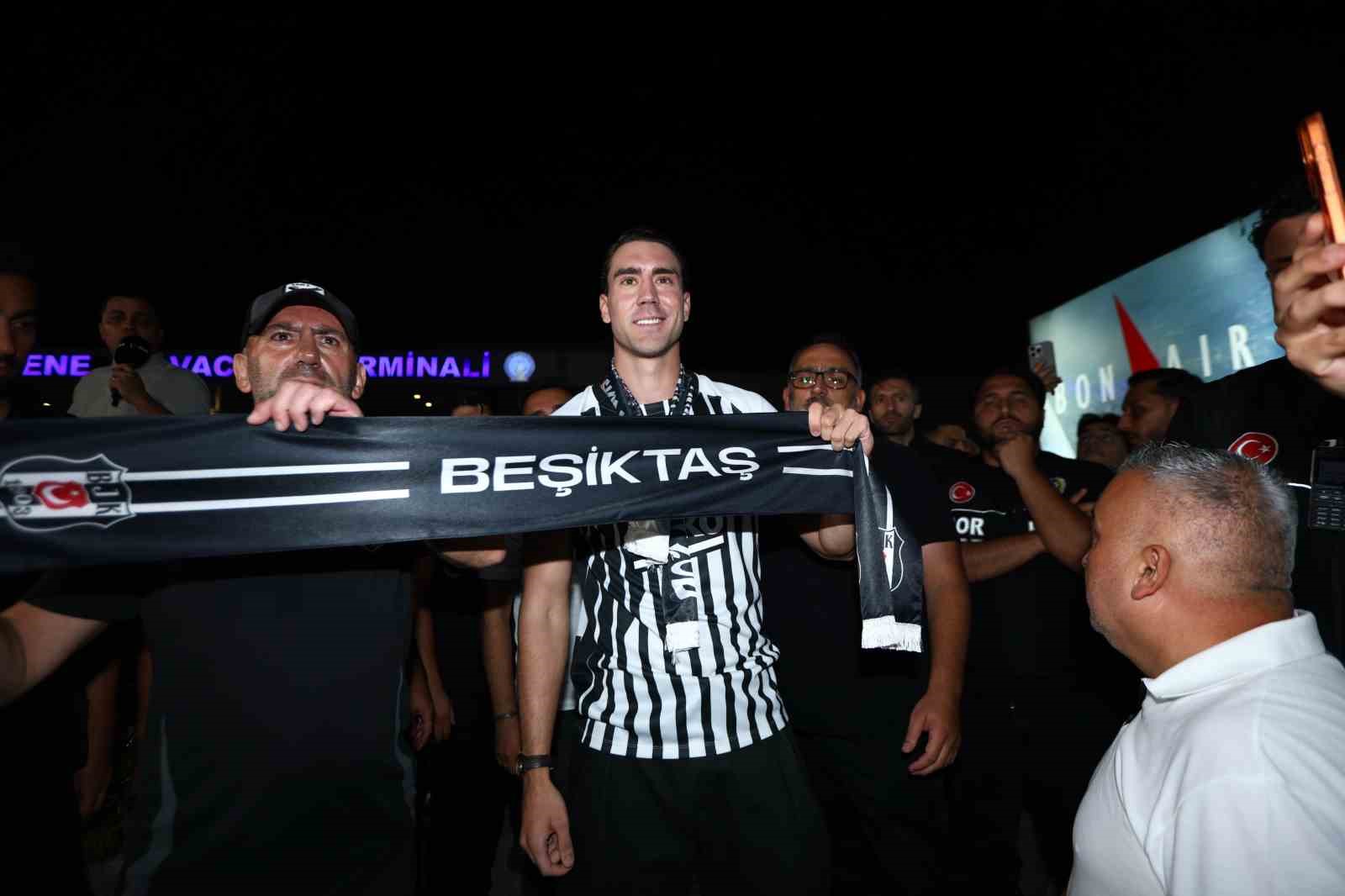 Dusan Vlahovic, gece saatlerinde Beşiktaş atkısı tutarak kameraların karşısında gülümsüyor.